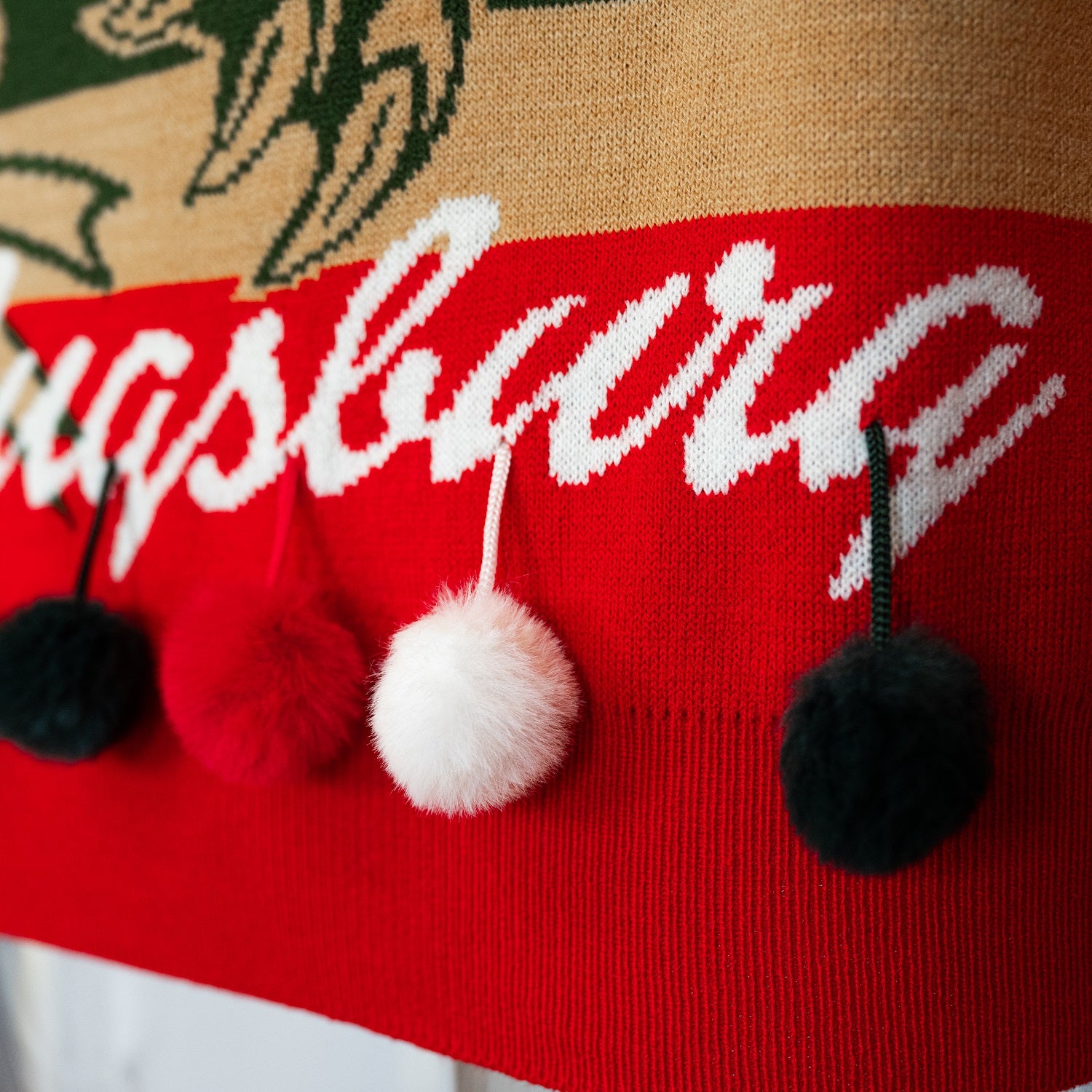 Fokus auf die rot-grün-weißen Bommel, angelehnt an Weihnachtskugeln, die auf dem Bauch baumeln. 