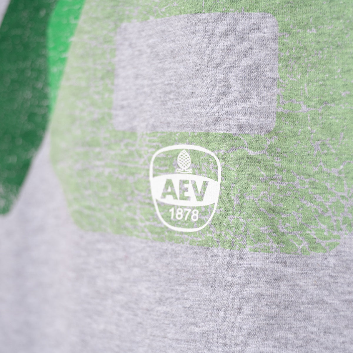 Nahaufnahme des AEV-Logos an der Unterseite des Shirts