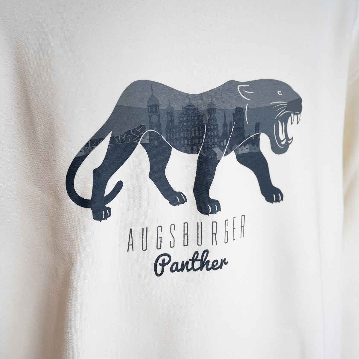 Cremeweißer Sweater mit Panther, in welchem eine Skyline von Augsburg zu sehen ist. Darunter steht "Augsburger Panther".