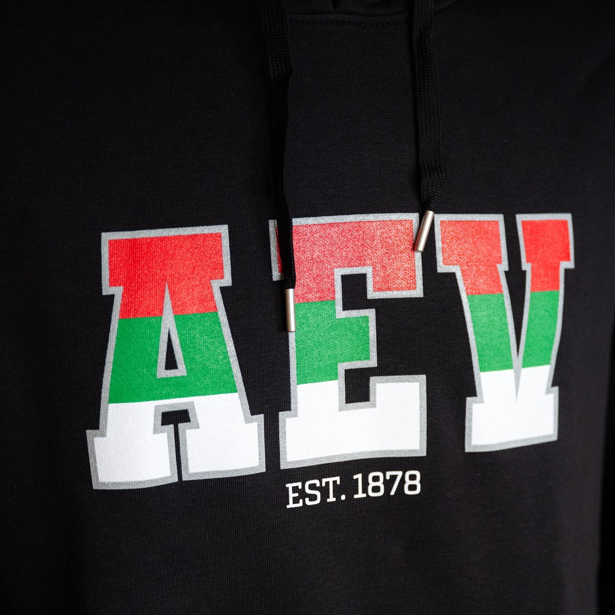 Nahaufnahme "AEV" Print in rot-grün-weiß. Darunter in klein geschrieben "Est. 1878"