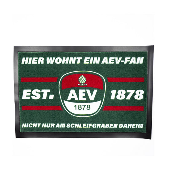 Fußmatte mit AEV Logo in der Mitte und Schriftzug "Hier wohnt ein AEV-Fan" oben, sowie "Nicht nur am Schleifgaben daheim". Neben dem AEV-Logo "Est. 1878"