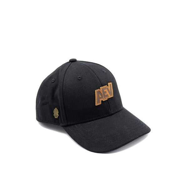 schwarze Cap mit AEV-Stick und Zirbelnuss-Pin an der Seite